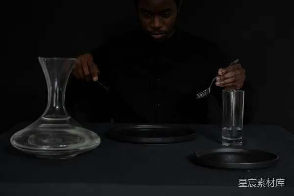 高清摄影 一个男人坐在桌前，面前有一盘食物和一杯饮料。