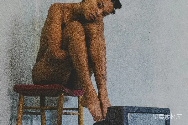 高清摄影 一个赤裸的男人坐在电视机旁边的椅子上。