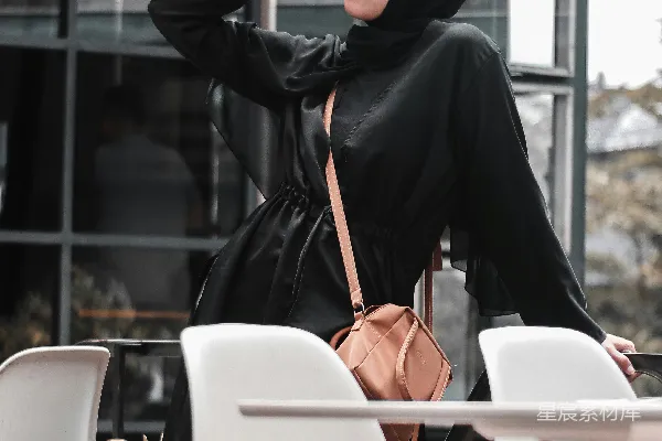 高清摄影 头戴黑色头巾和阿伯阿耶的女人坐在白色的椅子上。