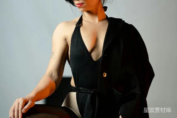 高清摄影 穿着黑色泳衣和西装外套的女人坐在椅子上摆姿势。