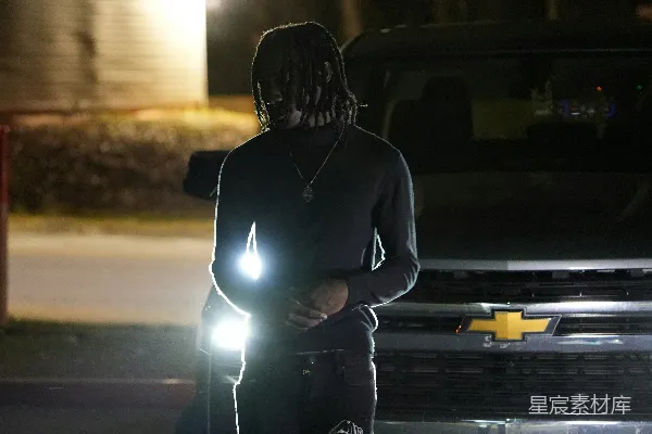 高清摄影 一个男人站在卡车前，手里拿着手电筒。
