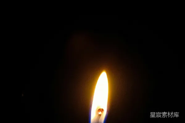 高清摄影 一盏点燃的蜡烛在黑暗中，背景是黑色。