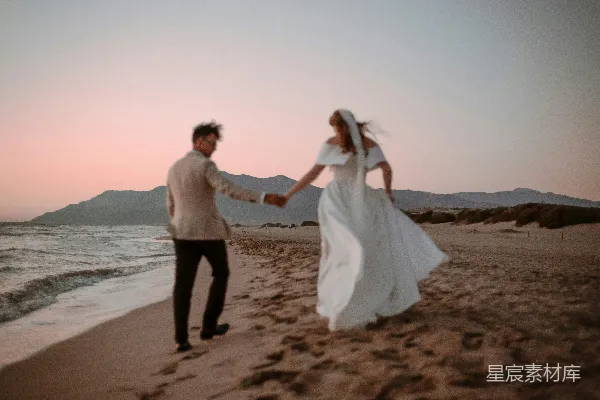 高清摄影 新婚夫妇在日落时分沿着海滩奔跑。
