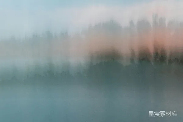 高清摄影 模糊的照片，背景中有树木，前景是一片水域。