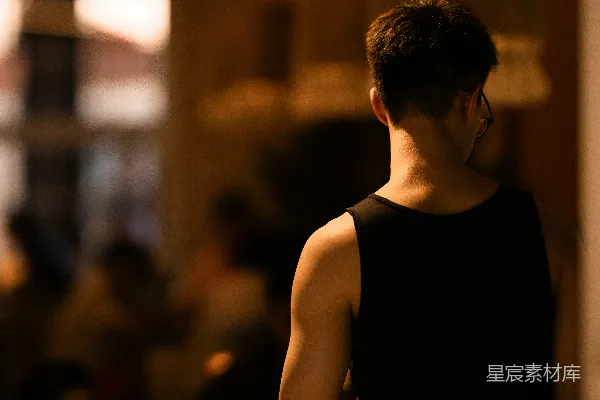高清摄影 一个穿着黑色背心的男人站在房间里。