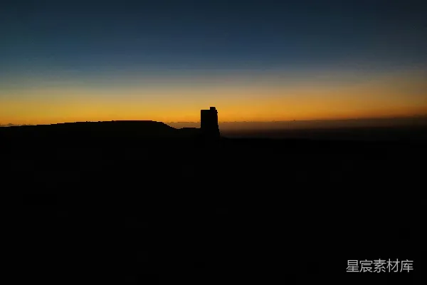 高清摄影 夕阳西下时，山丘上矗立着一座塔的剪影。