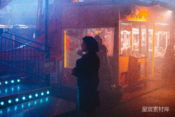 高清摄影 一个女人站在夜晚的嘉年华摊位前。