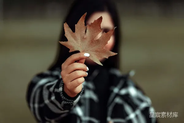 高清摄影 一个年轻女孩手里拿着一片叶子。