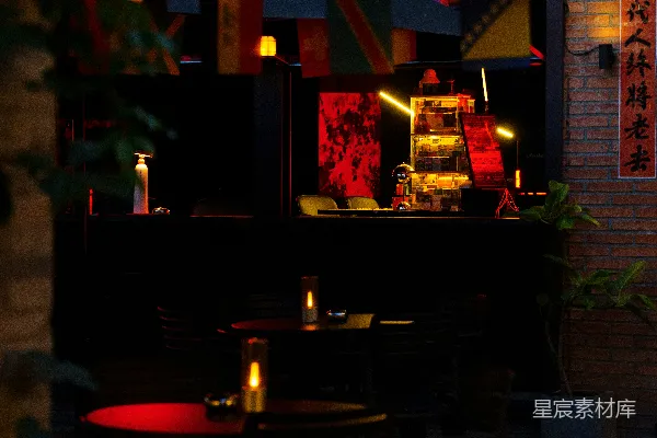 高清摄影 昏暗的户外咖啡馆，红色的桌子和建筑的灯光都亮着。