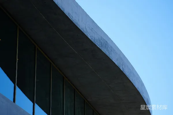 高清摄影 线条流畅的混凝土建筑，配有反光窗户和蓝天。