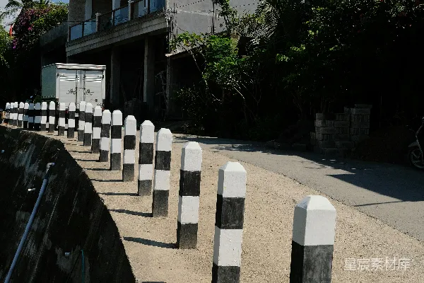 高清摄影 黑白相间的路障排列在一条阳光明媚的道路上。