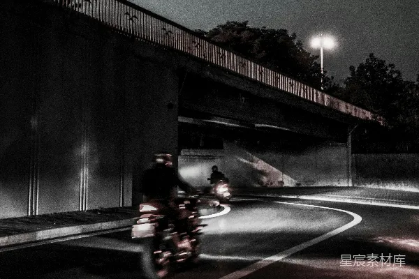高清摄影 一个男人在夜晚沿着街道骑摩托车。