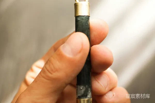 高清摄影 一只手拿着一个金属物体，上面放着一块岩石。
