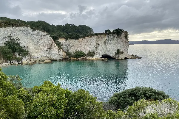 高清摄影 白天，蓝天白云下，蓝海上有岩石山旁的绿树。