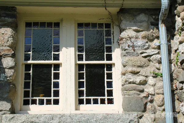 高清摄影 一座石头建筑，有两扇窗户和一根管道。