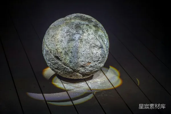 高清摄影 一块风化的圆形石头放在木制表面上。