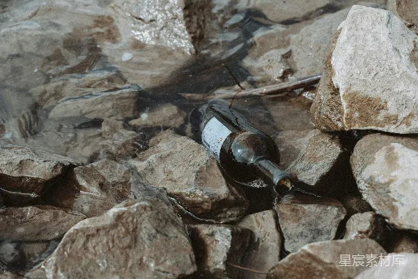 高清摄影 一瓶酒摆放在一堆岩石上。