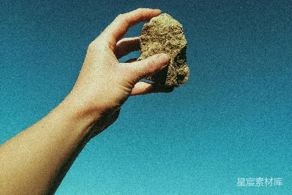 高清摄影 在蓝天下的白天，一个人拿着一块棕色的岩石。