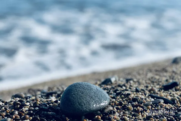 高清摄影 一块岩石坐落在海滩上，旁边是大海。