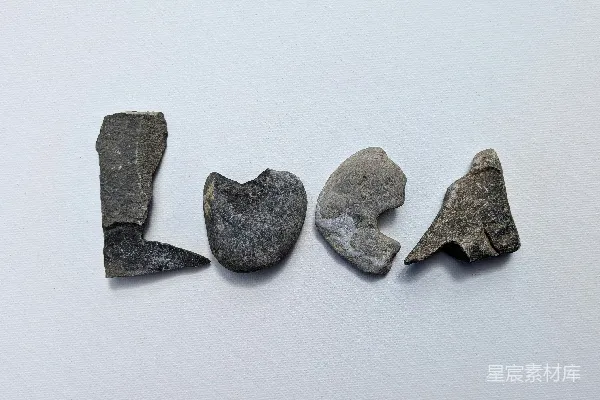 高清摄影 灰色的石头在白色背景上拼出“loca”。