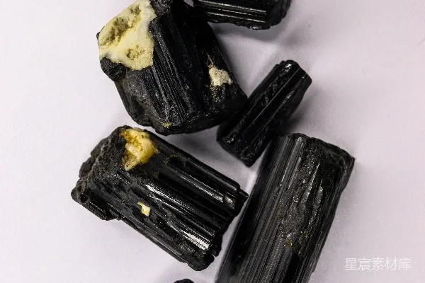 高清摄影 粗糙的黑色电气石晶体在白色表面上。