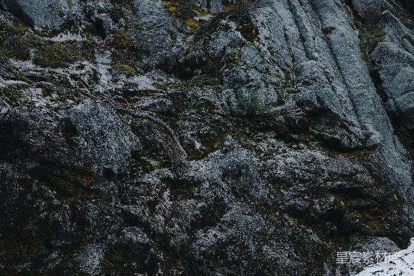 高清摄影 一块岩石峭壁，上面有苔藓和积雪的斑块。