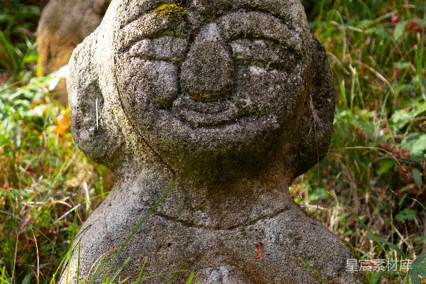 高清摄影 草地上的石雕，雕面上带着微笑。