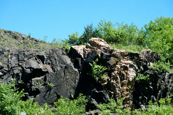 高清摄影 岩石山坡，有深色和浅色的岩石以及绿色的植被。