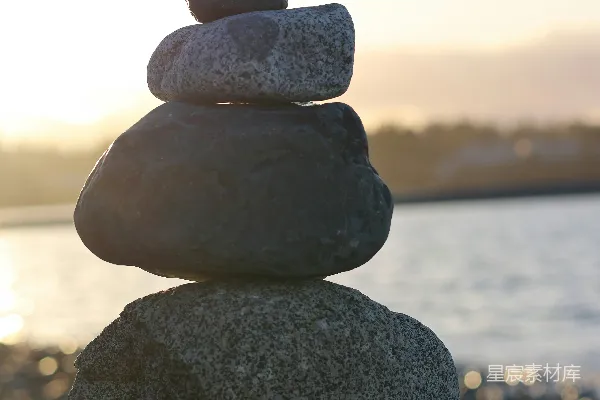 高清摄影 在夕阳下，海洋边的平衡石堆。