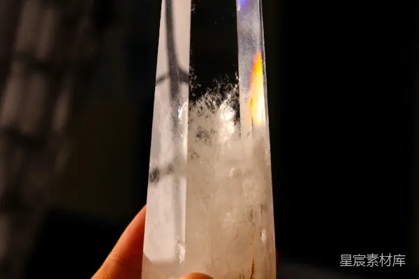 高清摄影 一只手拿着一块含有包裹体的透明水晶。