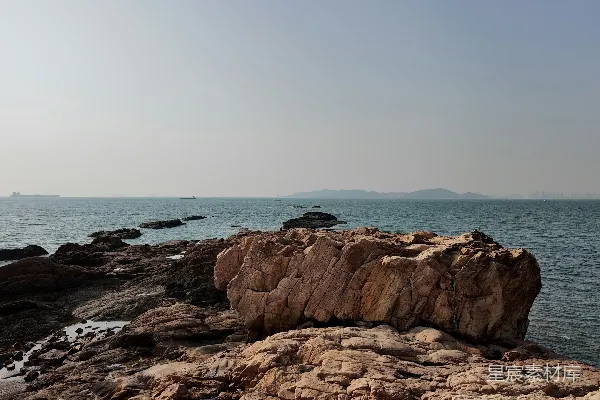 高清摄影 岩石海岸线，平静的海面在薄雾笼罩的天空下。