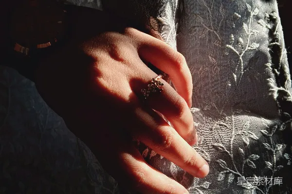 高清摄影 手戴戒指在阳光下放在织物上的女人的手。