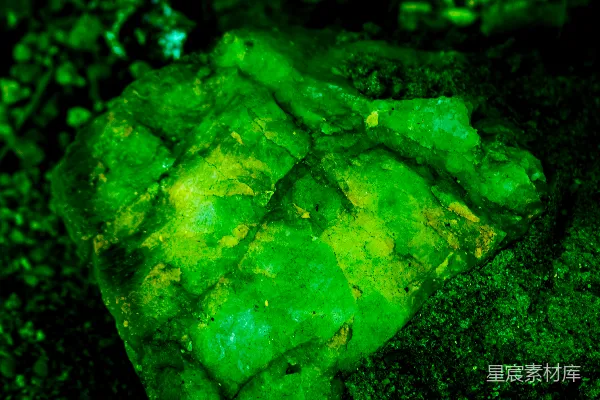 高清摄影 一块鲜亮的绿色矿石在黑暗的背景下发出光芒。