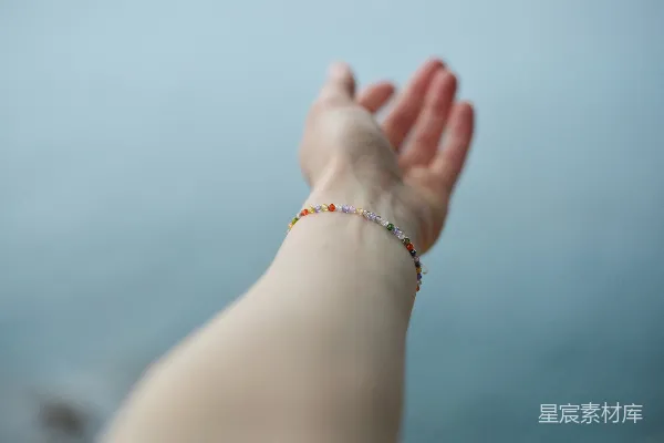 高清摄影 一只手伸展着，手腕上戴着串珠手链。