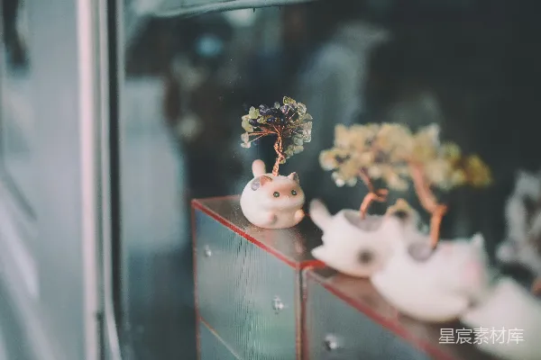 高清摄影 三只装饰用的小猫雕像，旁边有小树。