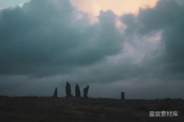 高清摄影 一群人在云层密布的天空下站在山顶上。