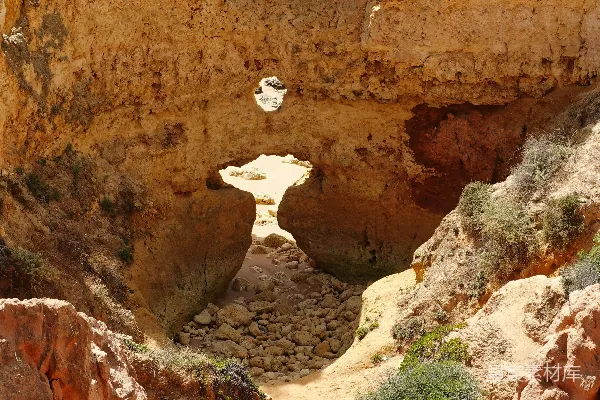 高清摄影 一座岩石峭壁，背景中有海滩和水。