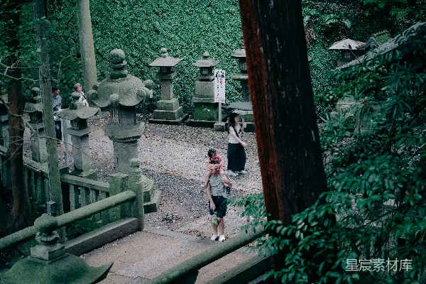 高清摄影 人们走在一条铺有石灯笼的路径上。
