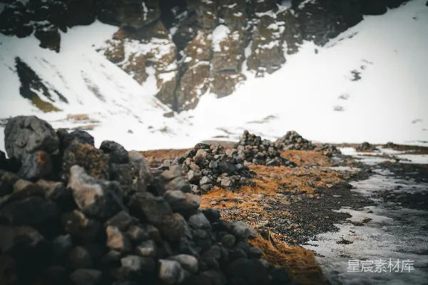 高清摄影 一堆岩石坐落在积雪覆盖的山顶一侧