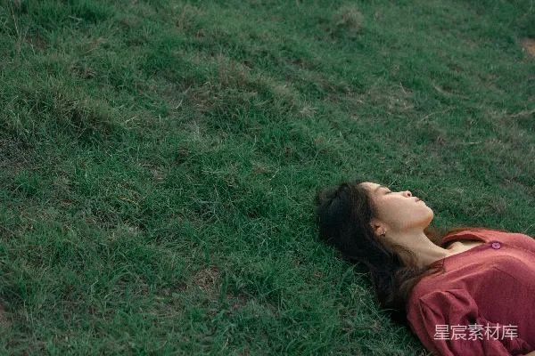 高清摄影 一个女人躺在草地上，闭着眼睛。