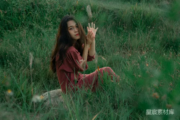 高清摄影 一个女人坐在田野里，双手举起来。