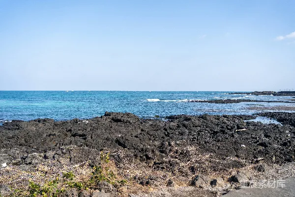 高清摄影 岩石海滩，背景中有一片水域。