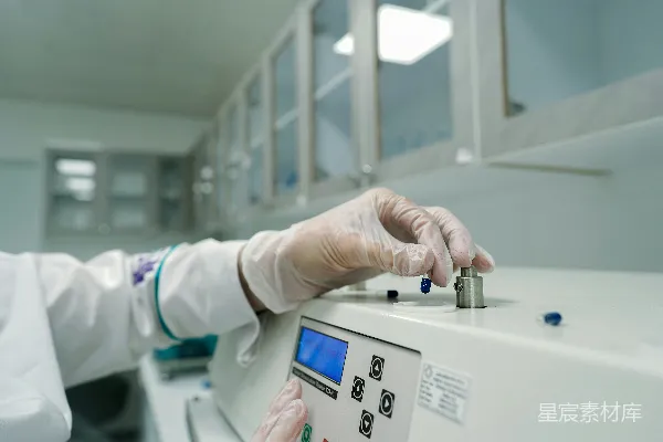 高清摄影 一个穿着实验室外套和戴着手套的人正在操作机器。