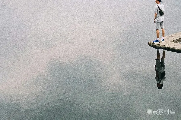 高清摄影 一个男人站在码头上，旁边是一片水域。