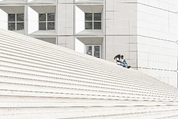 高清摄影 穿黑色夹克的男人坐在白天的白色混凝土地板上。