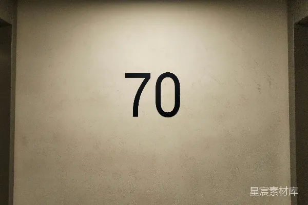 高清摄影 一面白墙上有黑色的数字“70”。