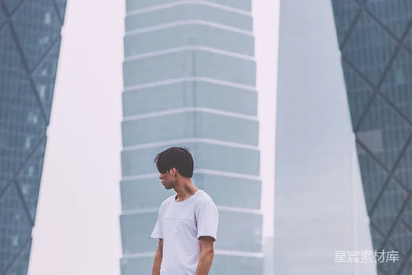 高清摄影 一个穿着白色圆领T恤的男人站在建筑物附近。