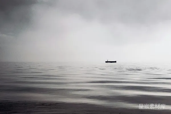 高清摄影 一个暗色的物体漂浮在平静的水面上，天空布满了云彩。