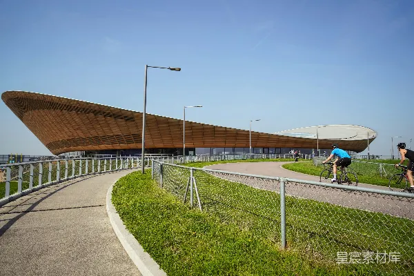 高清摄影 两个骑自行车的人在体育场附近的道路上白天骑行。
