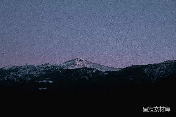 高清摄影 一座覆盖着积雪的山峰，背景是紫色的天空。